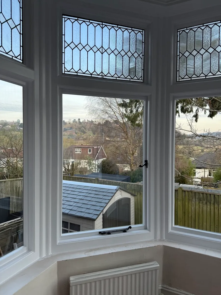 Interior bay window with leaded stained-glass top lights overlooking a valley view